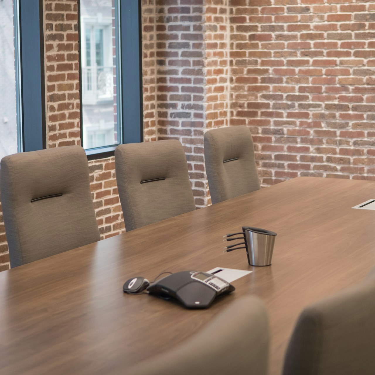 A quiet boardroom with a long wooden table and upholstered chairs